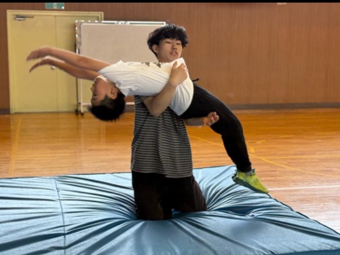 プロパルクール選手の指導の元バク転を練習する小学生